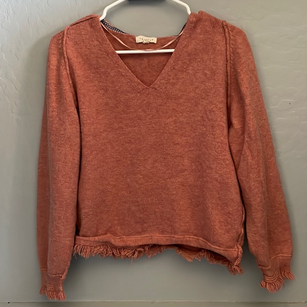 Red sweater with frayed bottom detail. Short in length but not a crop top.